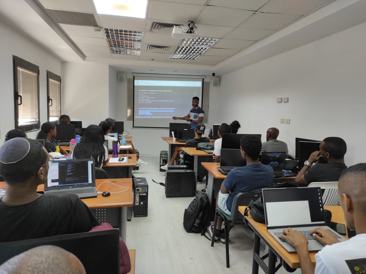 Yonatan leading a programming lesson with Tech-Career students working at their laptops.